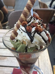 Eisbecher Ein köstlicher Eisbecher mit Sahne, Schokoladensoße, Nüssen und zwei knusprigen Schokoröllchen.