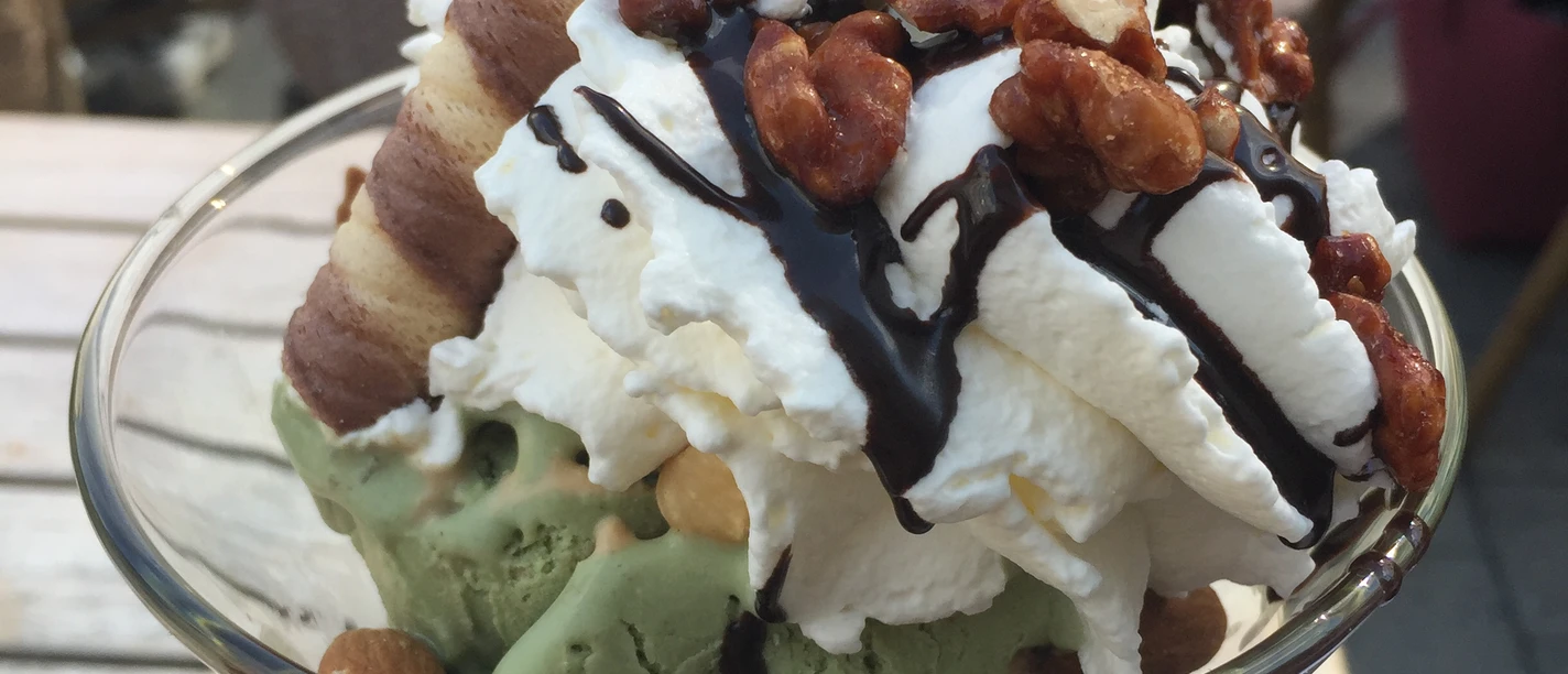 Eisbecher Ein köstlicher Eisbecher mit Sahne, Schokoladensoße, Nüssen und zwei knusprigen Schokoröllchen.