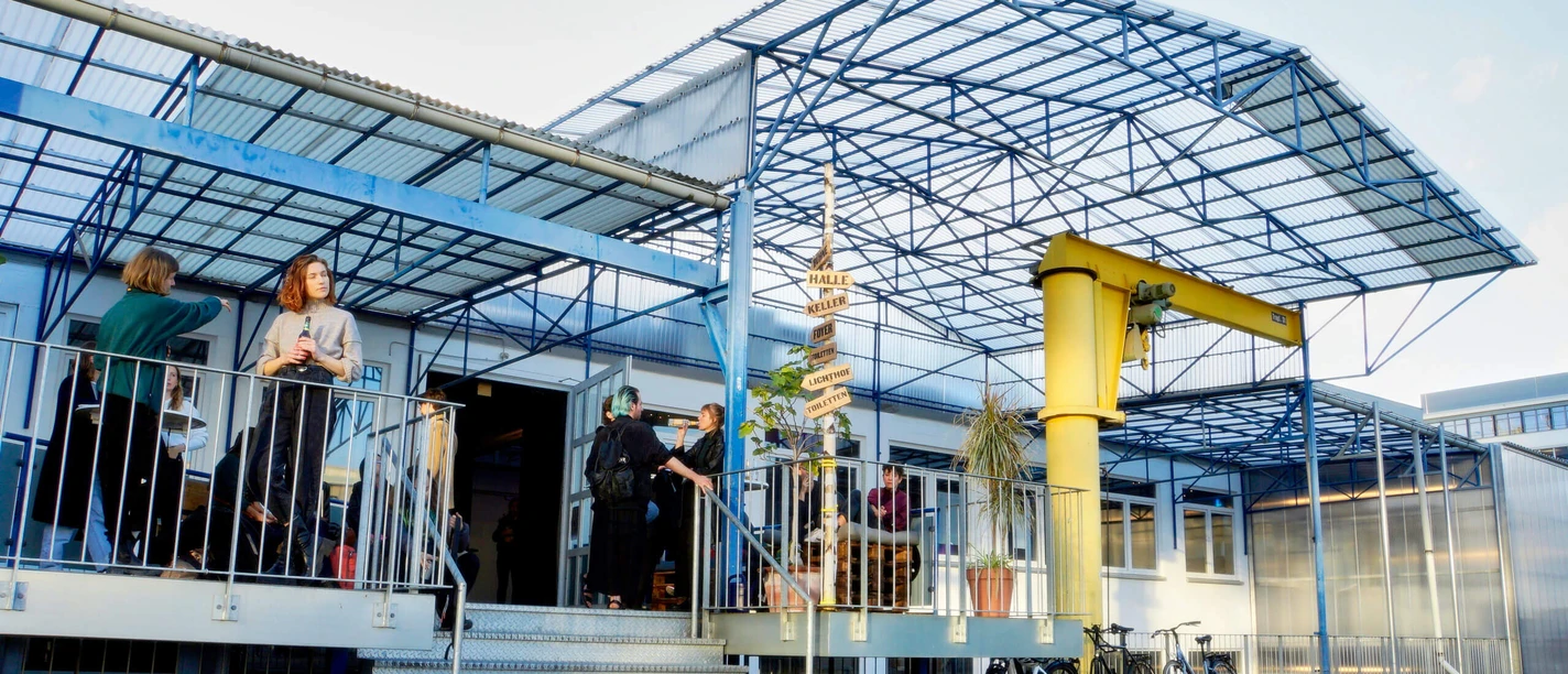 TanzFaktur - Außenansicht Außenbereich der TanzFaktur mit blauem Stahlgerüst, Treppe, Gästen und Fahrrädern