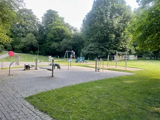 Freizeitpark Lindlar Spiel- und Fitnessgeräte im Freizeitpark Lindlar, umgeben von Wiese und hohen Bäumen