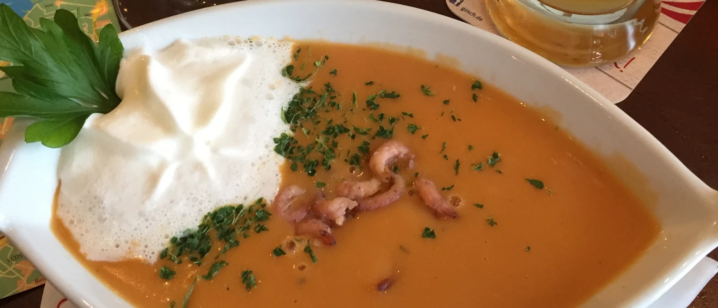 Fischsuppe Cremige Fischsuppe mit Meeresfrüchten und Sahnehaube, serviert mit frischem Baguette auf einem Tisch.