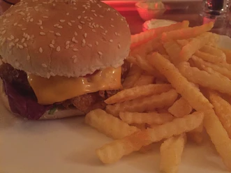 Burger Ein saftiger Burger mit geschmolzenem Käse, serviert neben einer Portion knuspriger Pommes Frites.