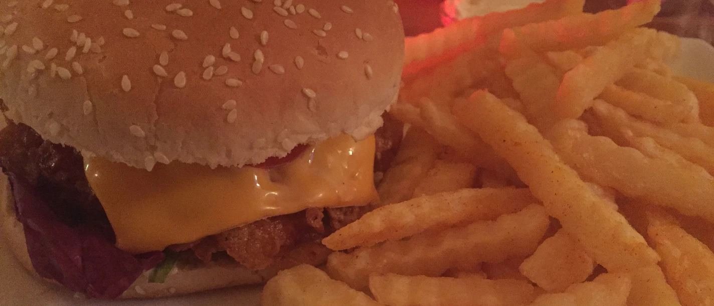 Burger Ein saftiger Burger mit geschmolzenem Käse, serviert neben einer Portion knuspriger Pommes Frites.