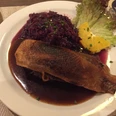 Entenbrust Entenbrust in dunkler Sauce mit Rotkohl, dekoriert mit Salat und Orangenscheiben auf einem Teller.