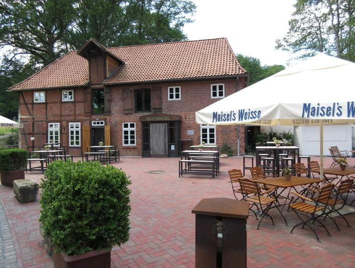 Klostermühle Heiligenberg Backsteingebäude mit rotem Dach und Holzelementen, umgeben von Bäumen und Außensitzbereich.