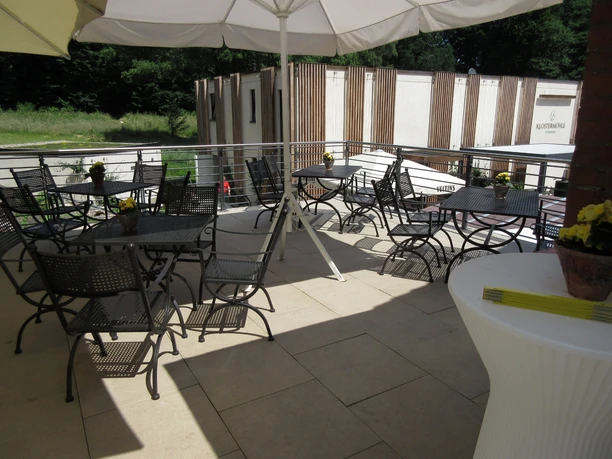 Klostermühle Heiligenberg Überdachte Terrasse der Klostermühle Heiligenberg mit leeren Tischen und Stühlen bei sonnigem Wetter.
