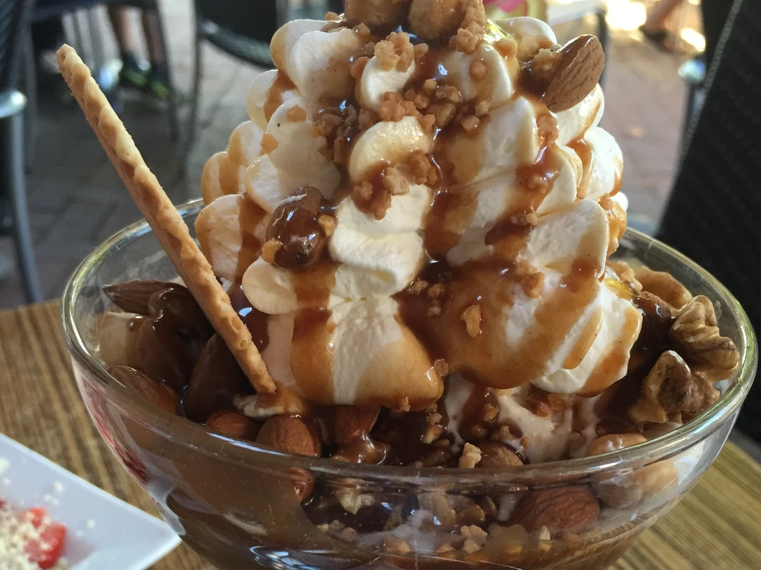 Köstlicher Eisbecher mit Sahne, Karamellsauce und knackigen Nüssen, serviert in einer Glasvase.Delicious sundae with cream, caramel sauce and crunchy nuts, served in a glass vase.Lækker sundae med fløde, karamelsauce og knasende nødder, serveret i en glasvase.Heerlijke sundae met room, karamelsaus en knapperige noten, geserveerd in een glazen vaas.