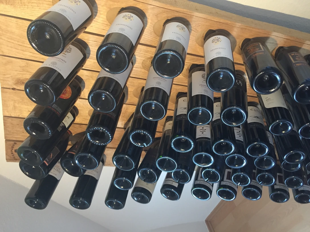 Weinregal Eine Vielzahl von Weinflaschen lagert waagerecht in einem Holzregal mit Blick auf die Flaschenböden.A large number of wine bottles are stored horizontally in a wooden rack with a view of the bottle shelves.Et stort antal vinflasker opbevares vandret i en træreol med udsigt til flaskehylderne.Een groot aantal wijnflessen wordt horizontaal opgeslagen in een houten rek met zicht op de flessenrekken.