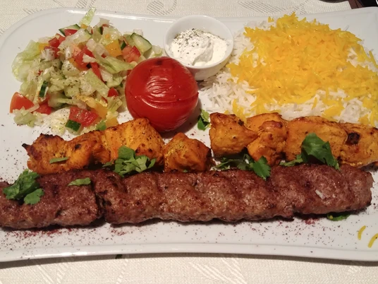 Orientalisch Ein persisches Gericht mit saftigem Kebab, Safran-Reis, gegrilltem Gemüse und frischem Beilagensalat.