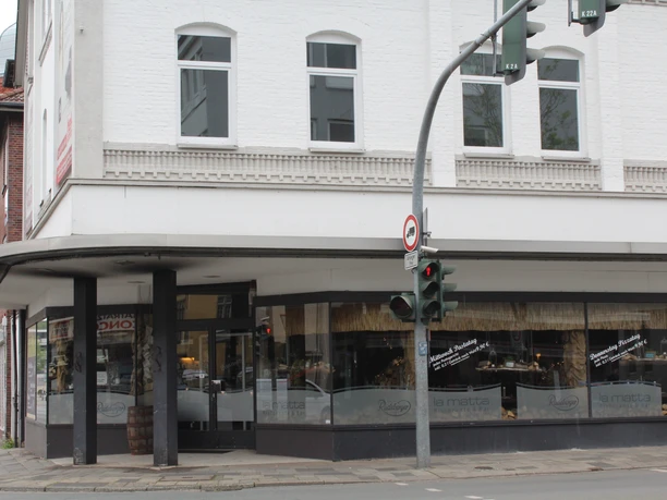An Italian restaurant with modern glass fronts on a street corner reflects urban flair.