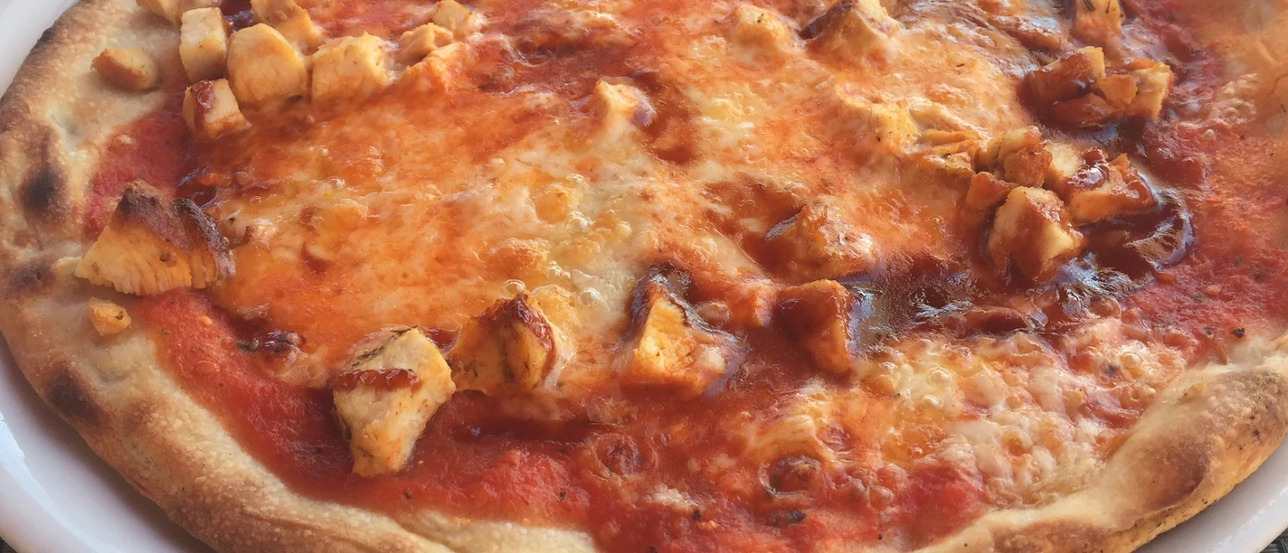 Pizza Frisch gebackene Pizza mit goldbraunem Rand, saftiger Tomatensauce und zarten Hähnchenstücken.