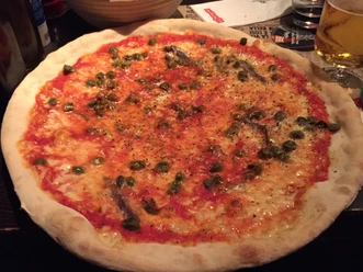 Grote pizza met een dunne, knapperige bodem, belegd met tomatensaus, kaas, kappertjes en ansjovis.