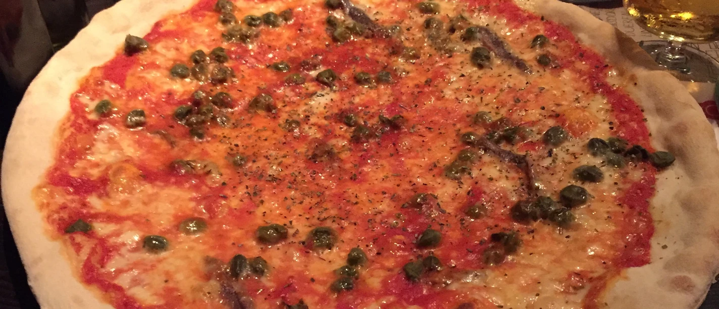 Pizza Große Pizza mit dünnem, knusprigem Boden, belegt mit Tomatensauce, Käse, Kapern und Sardellen.