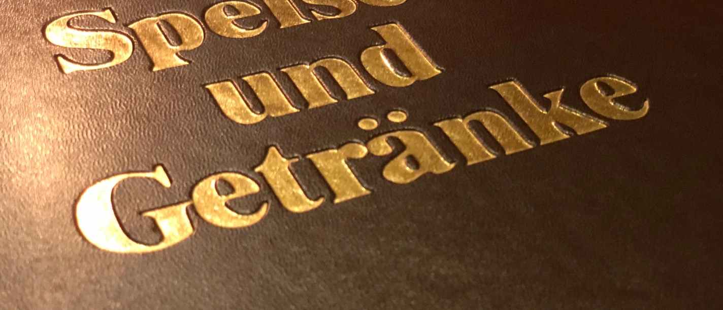 Speisen&Getränkekarte Goldene Buchstaben auf dunklem Hintergrund kennzeichnen die Speisen- und Getränkekarte eines Restaurants.