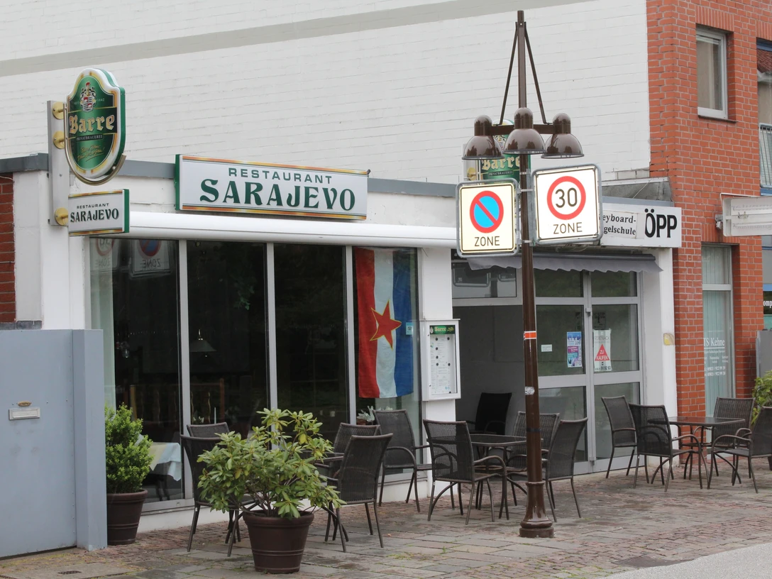 Restaurant Sarajevo Einladendes Restaurant mit Außenterrasse, dekoriert mit einer Balkan-Flagge, in urbaner Umgebung.