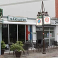 Restaurant Sarajevo Einladendes Restaurant mit Außenterrasse, dekoriert mit einer Balkan-Flagge, in urbaner Umgebung.