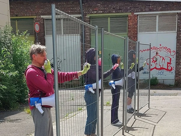 NO GO Performer mit Zaunelementen bei der Open-Air-Aufführung NO GO in Köln-Deutz