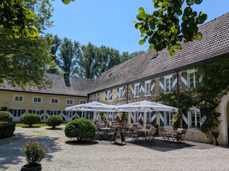 Im Innenhof liegende Terrasse des Burgcafés Haus Graven in Langenfeld Sonnige Außenterrasse des Burgcafés Haus Graven im Innenhof mit Tischen und Schirmen vor den historischen Gebäuden der Wasserburg.
