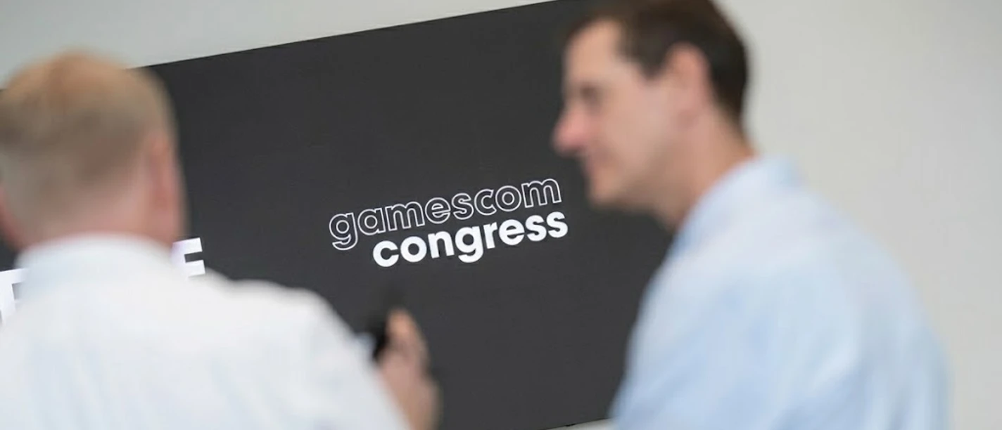 gamescom congress Blurred participants in front of a monitor displaying the "gamescom congress" logo