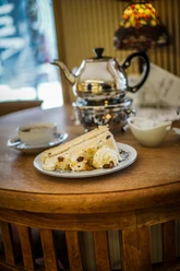 Antik Café Das Bild zeigt ein Teekännchen, Tasse Tee und Stück Torte