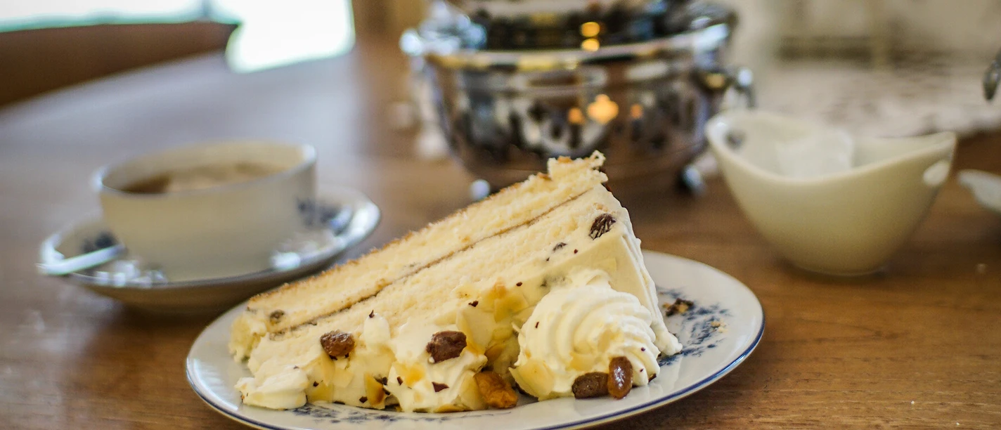 Antik Café Das Bild zeigt ein Teekännchen, Tasse Tee und Stück Torte