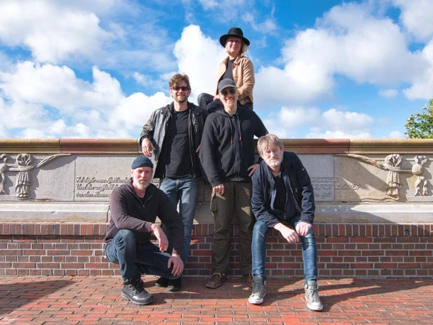 Van´t Siel Musik.jpeg Die fünfköpfige Band Van't Siel posiert draußen vor einer Steinmauer unter blauem Himmel.