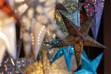 Adventszeit in Köln Bunte, leuchtende Papiersterne an einem Weihnachtsmarktstand