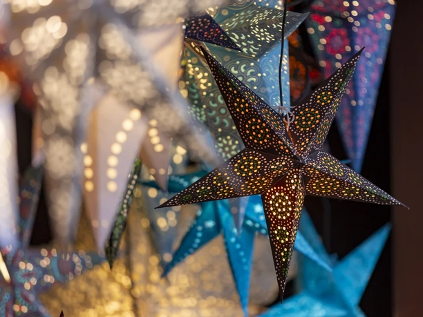 Adventszeit in Köln Bunte, leuchtende Papiersterne an einem Weihnachtsmarktstand
