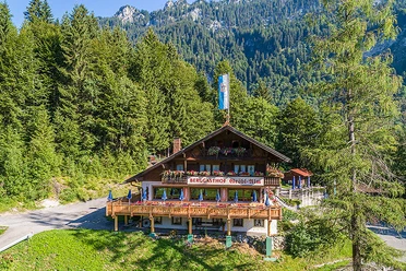 Gröbl Alm Berggasthof Gröbl Alm mit Holzterrasse vor Wald und Bergen in Graswang