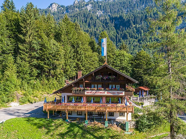 Gröbl Alm Berggasthof Gröbl Alm mit Holzterrasse vor Wald und Bergen in Graswang