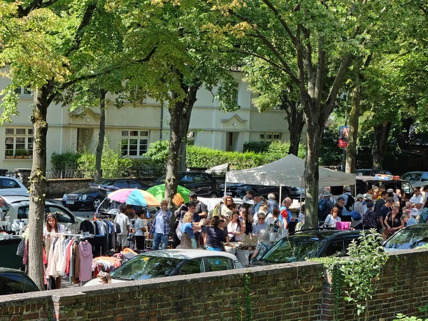 Belebter Flohmarkt unter Bäumen im Kölner Stadtteil Riehl mit Ständen und Besuchern