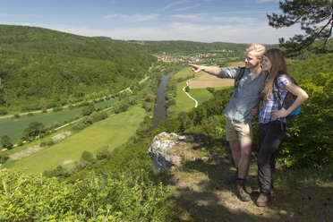 Am Engelsfels/Gemeinde Duggendorf Zwei Wanderer stehen auf einem Felsen und blicken über ein grünes Tal mit Fluss.