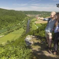 Am Engelsfels/Gemeinde Duggendorf Zwei Wanderer stehen auf einem Felsen und blicken über ein grünes Tal mit Fluss.