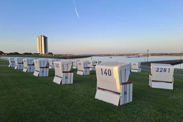 Qi Gong am Meer - Kraftvoll und entspannt ins Wochenende Strandkörbe am Deich. Im Hintergrund ein Hochhaus.