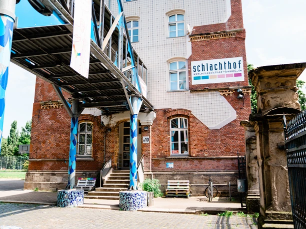 Das Backsteingebäude vom Kulturzentrum Schlachthof in Kassel ist sichtbar. Rechts im Bild befindet sich das Eingangstor zum Kulturzentrum Schlachthof.
