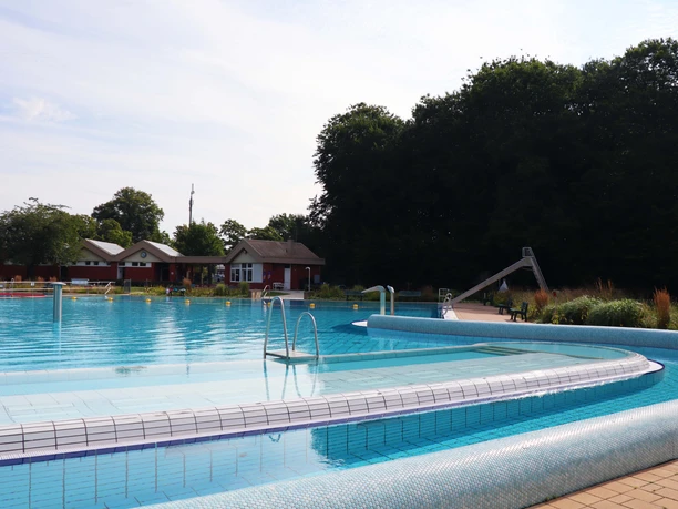 Freibad Hunteholz Barnstorf Schwimmbecken.jpg Die Becken des Freibads Hunteholz an einem sonnigen Tag mit Bäumen und einer Rutsche.