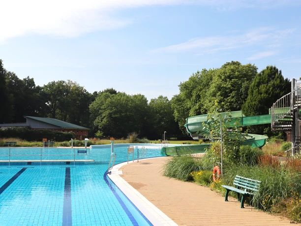 Freibad Hunteholz Barnstorf Rutsche.jpg Das Schwimmbecken des Freibads Hunteholz mit der grünen Wasserrutsche, umgeben von Bäumen.