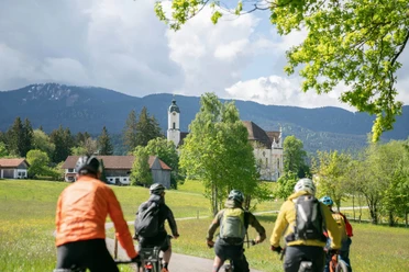 RadKultTouren Wieskirchrunde E-Bike Gruppe fährt durch grüne Voralpenlandschaft zur Wieskirche.