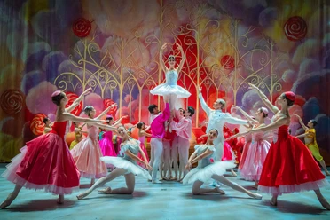 A ballet scene from *The Nutcracker* featuring dancers in colorful costumes against a fairy-tale backdrop