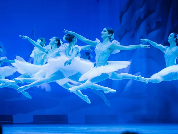 Der Nussknacker - GRAND CLASSIC BALLET Ballerinen in weißen Tutus springen im blauen Bühnenlicht synchron über die Bühne