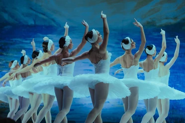 Schwanensee - Jenseits der Bühne Ballerinen in weißen Tutus tanzen Schwanensee vor blauem Bühnenbild