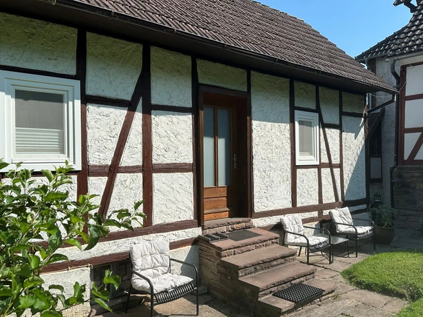 Außenansicht des Ferienhauses am Ritzberg 2 Frontansicht Fachwerkhaus mit zwei Fenstern und Haustür aus Holz, über Treppenstufen zu erreichen, Sitzbereich