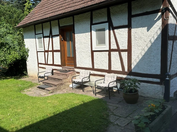 Außenansicht des Ferienhauses am Ritzberg 2 Frontansicht Fachwerkhaus mit zwei Fenstern und Haustür aus Holz, über Treppenstufen zu erreichen, Sitzbereich