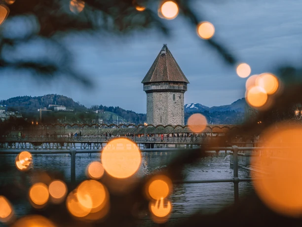 Lucerne’s Chapel Bridge and Water Tower framed by warm Advent lights at dusk