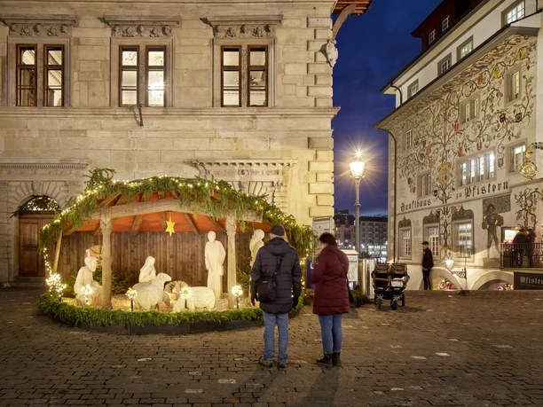 Beleuchtete Weihnachtskrippe am Kornmarkt in Luzern vor historischen Fassaden
