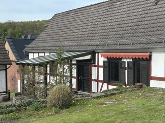 Außenansicht des Ferienhauses am Ritzberg Fachwerkhaus mit überdachtem Eingang, Fenster mit Fensterläden, Rasenfläche