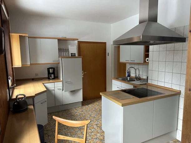 Küche des Ferienhauses am Ritzenberg Weiße Einbauküche über Eck mit Edelstahlesse, Cerankochfeld, Spüle und Kühlschrank