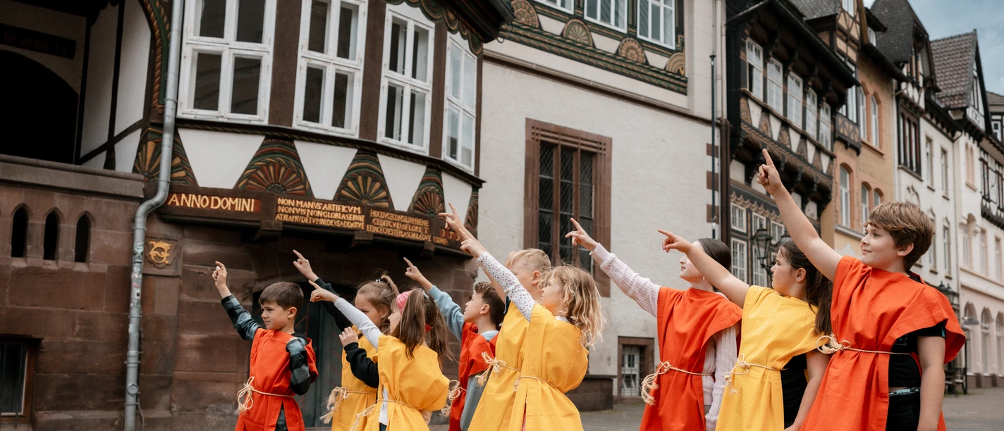 Kinder, Rallye, Führung, Rathaus Viele Kinder in orangen-gelben Kutten stehen auf dem Marktplatz und zeigen neugierig in dieselbe Richtung