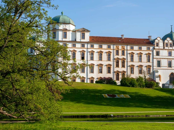 Celler-Schloss.jpg Celler Schloss mit weißen Fassaden, grünen Kuppeln und Parkwiese am Wasser