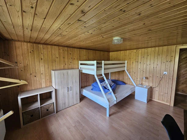 Ferienwohnung Kirchbühl Geräumiges Schlafzimmer mit Holzwänden, Etagenbett und Stauraum in rustikalem Stil